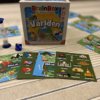 Spelet BrainBox Världen utlagt på ett bord. Låda, kort, timglas och tärning.